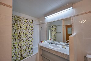 A bathroom with a shower, a sink, a mirror, and a toilet. - Cozy Family Getaway Home (Quillan)