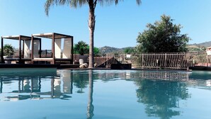 Una piscina cristalina con una palmera y una estructura de pérgola.