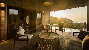 A wooden deck with a round table, chairs, and a sofa. - Zannier Bãi San Hô (Xuan Canh)