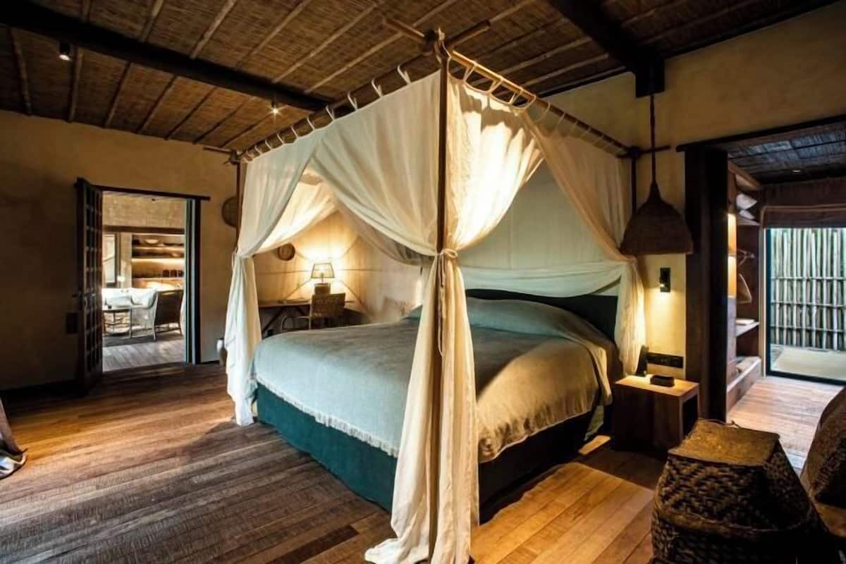Ein Zimmer mit einem Bett, einem Nachttisch, einer Lampe und einem gewebten Korb.