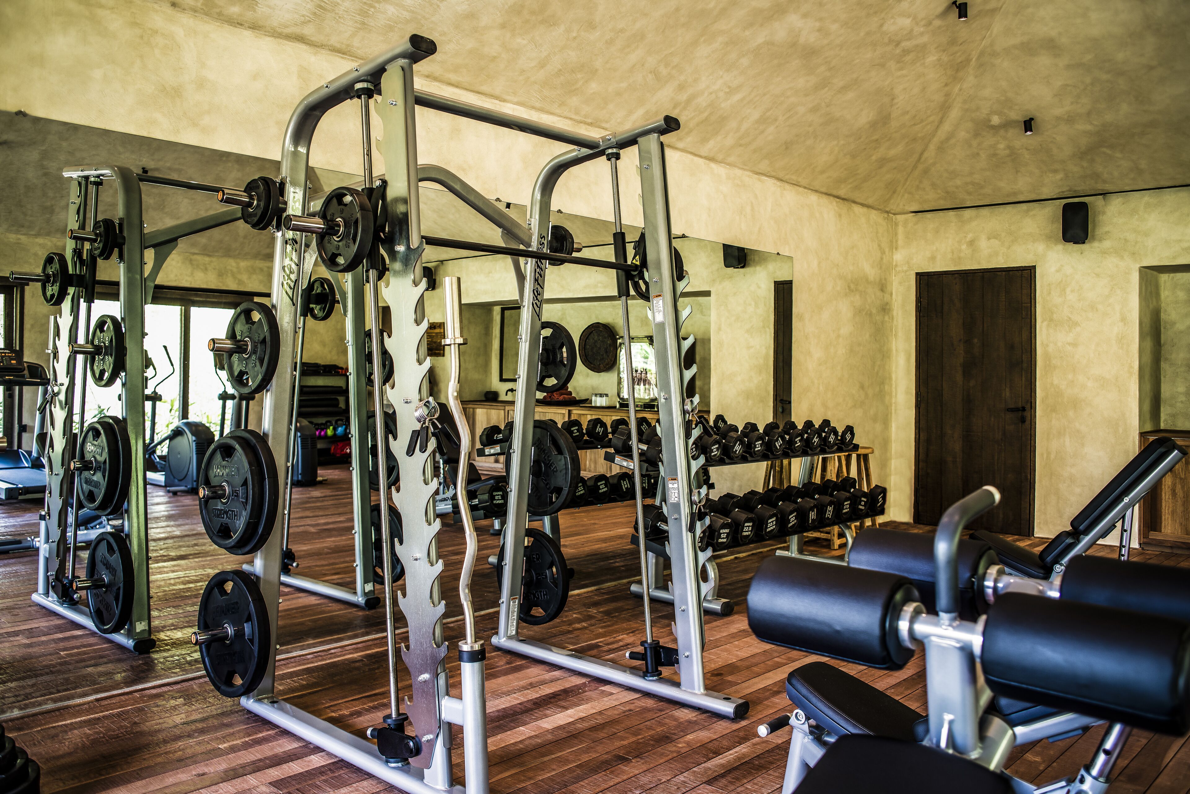 A gym with weightlifting equipment, benches, and dumbbells.