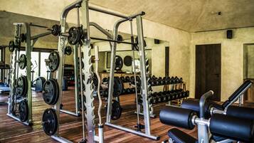 A gym with weightlifting equipment, benches, and dumbbells.