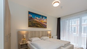 Ein modernes Hotelzimmer mit einem großen Bett, Nachttischen, einem Gemälde und Blick auf die Stadt.