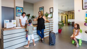 Ein Empfangsbereich mit Theke, eine Wartezone mit Sitzbank und ein Flur mit einer Tür.