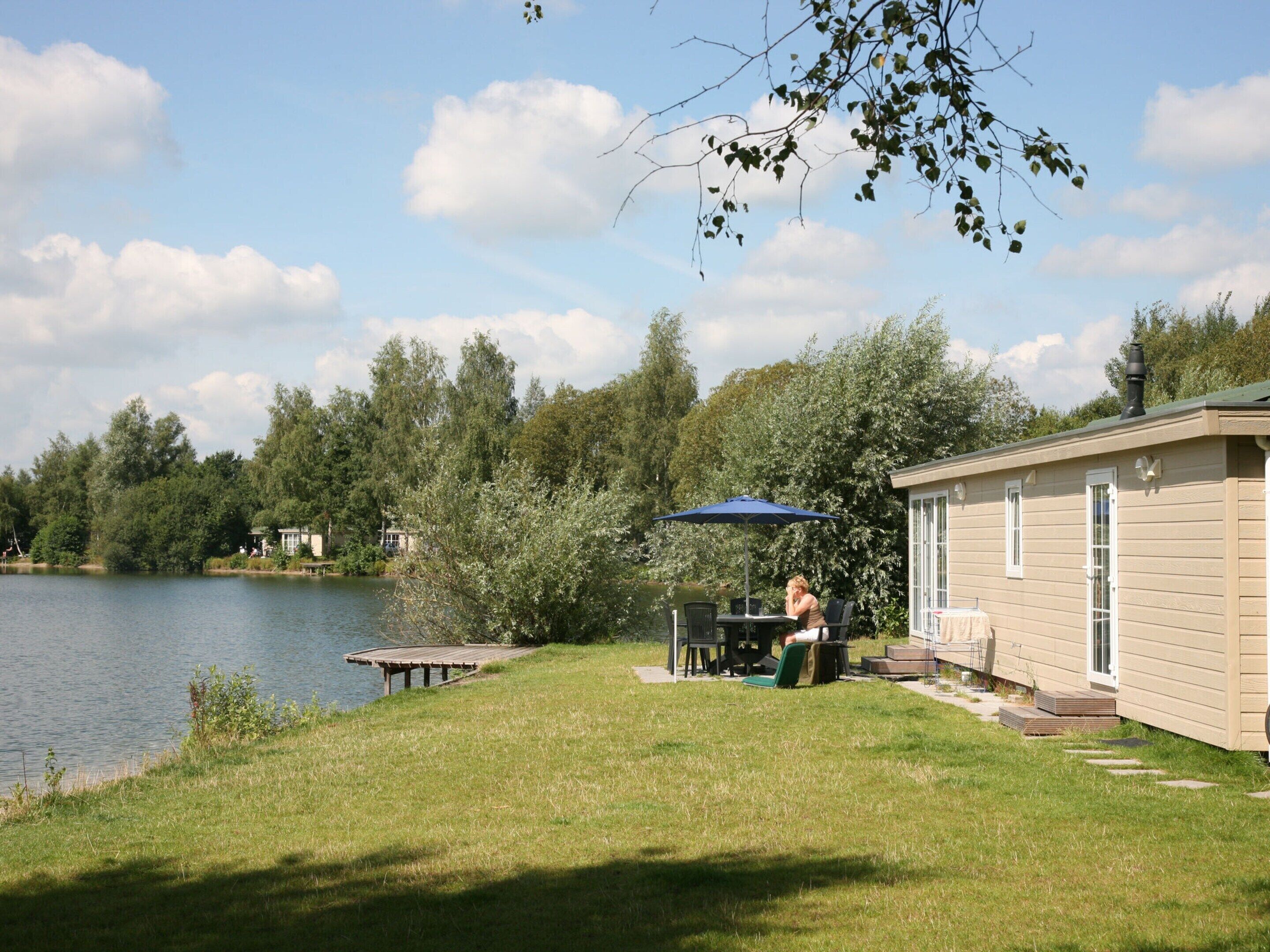 Une propriété située au bord du lac, comprenant un espace repas, des sièges extérieurs et un petit bâtiment.