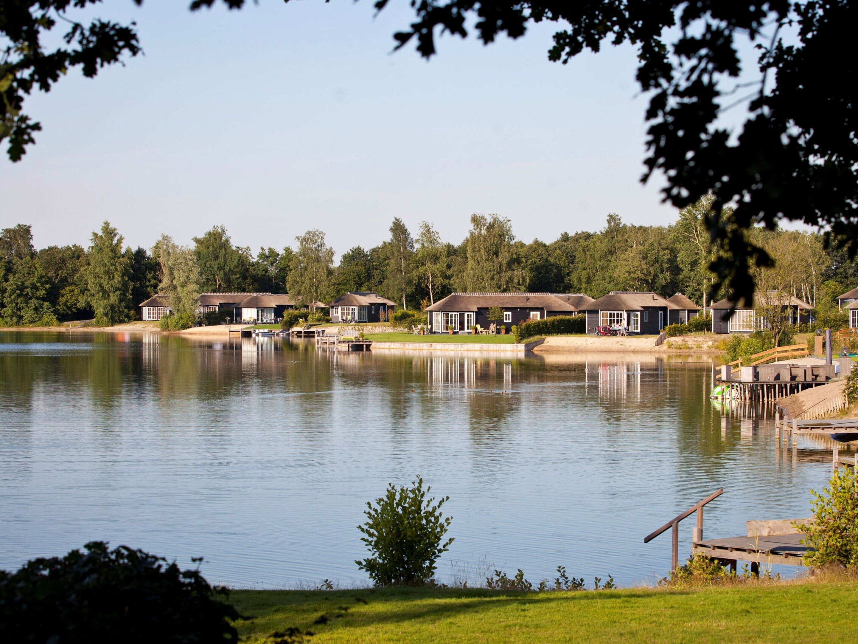 A lakeside property with multiple houses, docks, and a grassy area.