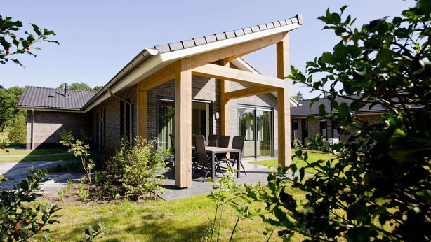 A modern house with a covered patio, a brick exterior, and a large glass door. - Terraced Home in Netherlands Near Veluwe (Voorthuizen)