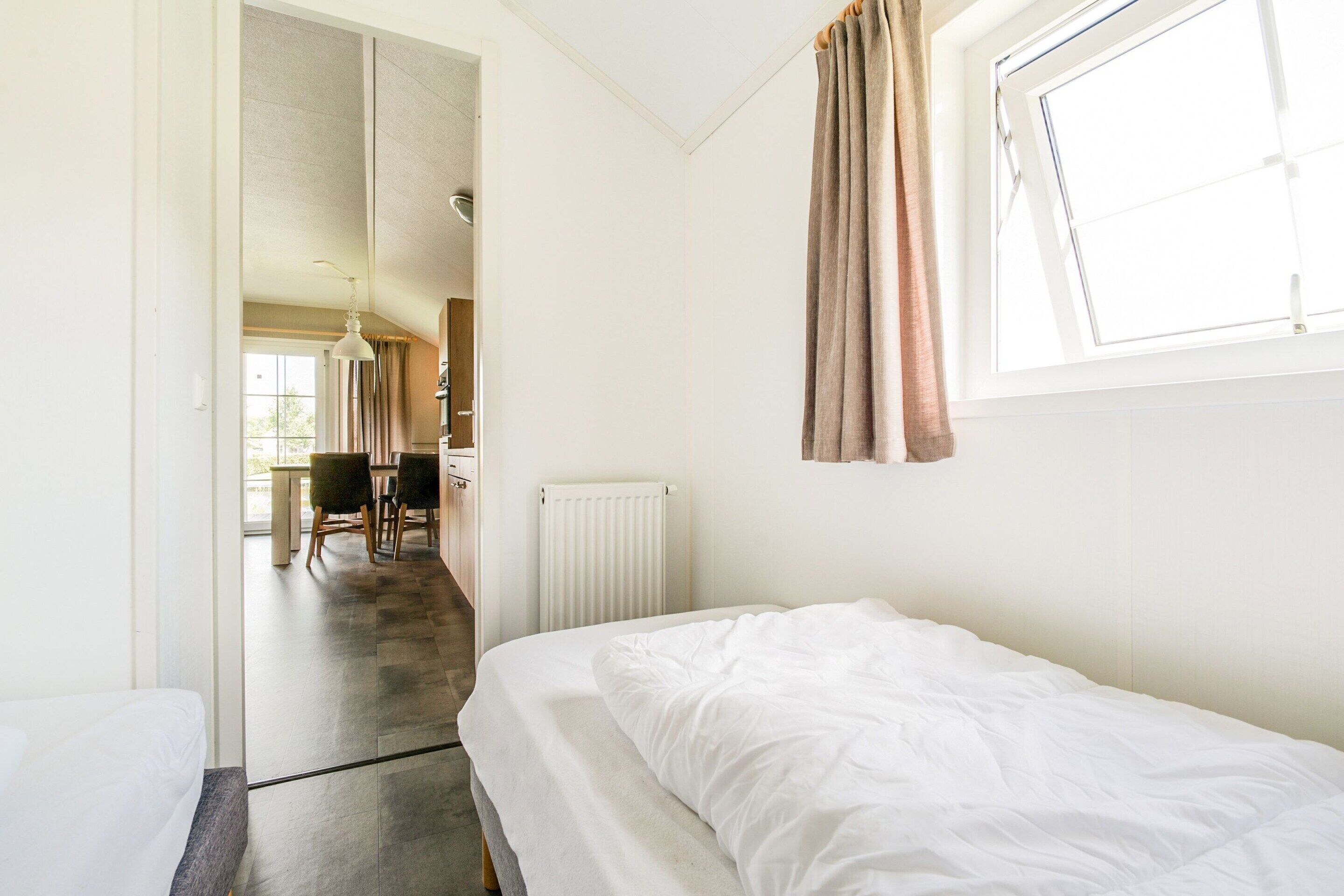Ein Hotelzimmer mit Bett, einem Vorhangfenster, einer Heizung und Blick auf den Speisesaal.