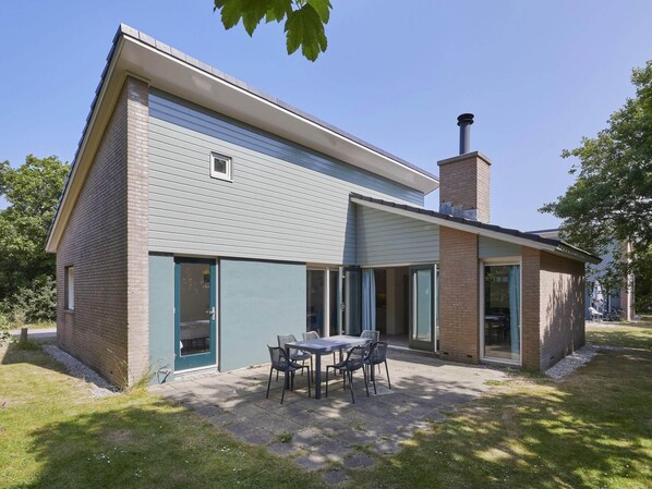 Et toetagers hus med en patio, hvor der er et bord og stole.