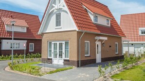 Ein modernes Wohngebäude mit roter Ziegeldach, weißen Fensterrahmen und einer Backsteinfassade.