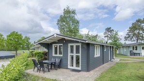 A small, single-story building with a patio area, a table, and chairs. - Apartment in Netherlands Near Nature Trails (Arcen)