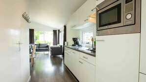 Eine moderne Küche mit weißen Schränken, einer eingebauten Mikrowelle und einem Essbereich mit Sofa und Tisch.