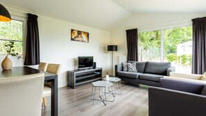 Ein modernes Wohnzimmer mit einer Couch, einem Esstisch, einem Fernseher und einer Lampe.