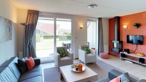 Un salon moderne avec un canapé, une table basse et un téléviseur. Une porte-fenêtre coulissante donne accès à un balcon.