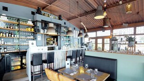 Un restaurant doté d’un bar, d’un plafond en bois et de grandes fenêtres.