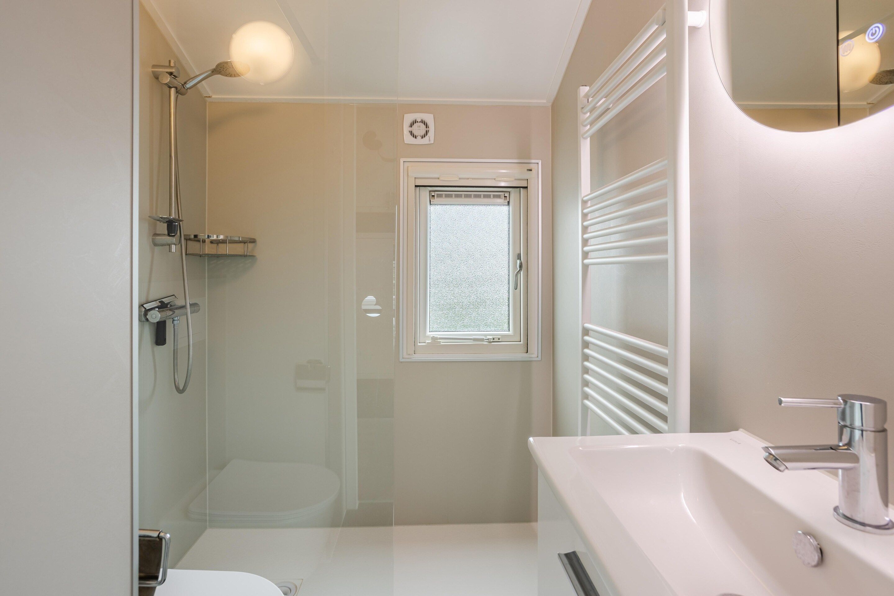 Une salle de bain avec douche, toilettes et lavabo.