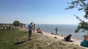 A beach with people relaxing, a dog, and a tent. - Modern Chalet Near Lake Sneek (Terkaple)