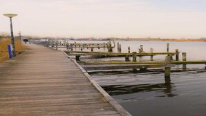 A wooden boardwalk extending into a body of water with a lamp post on the left. - Modern Chalet Near Lake Sneek (Terkaple)