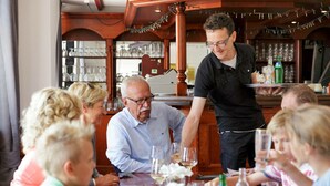 A group of people seated around a wooden table in a restaurant with a bar in the background. - Modern Chalet Near Lake Sneek (Terkaple)