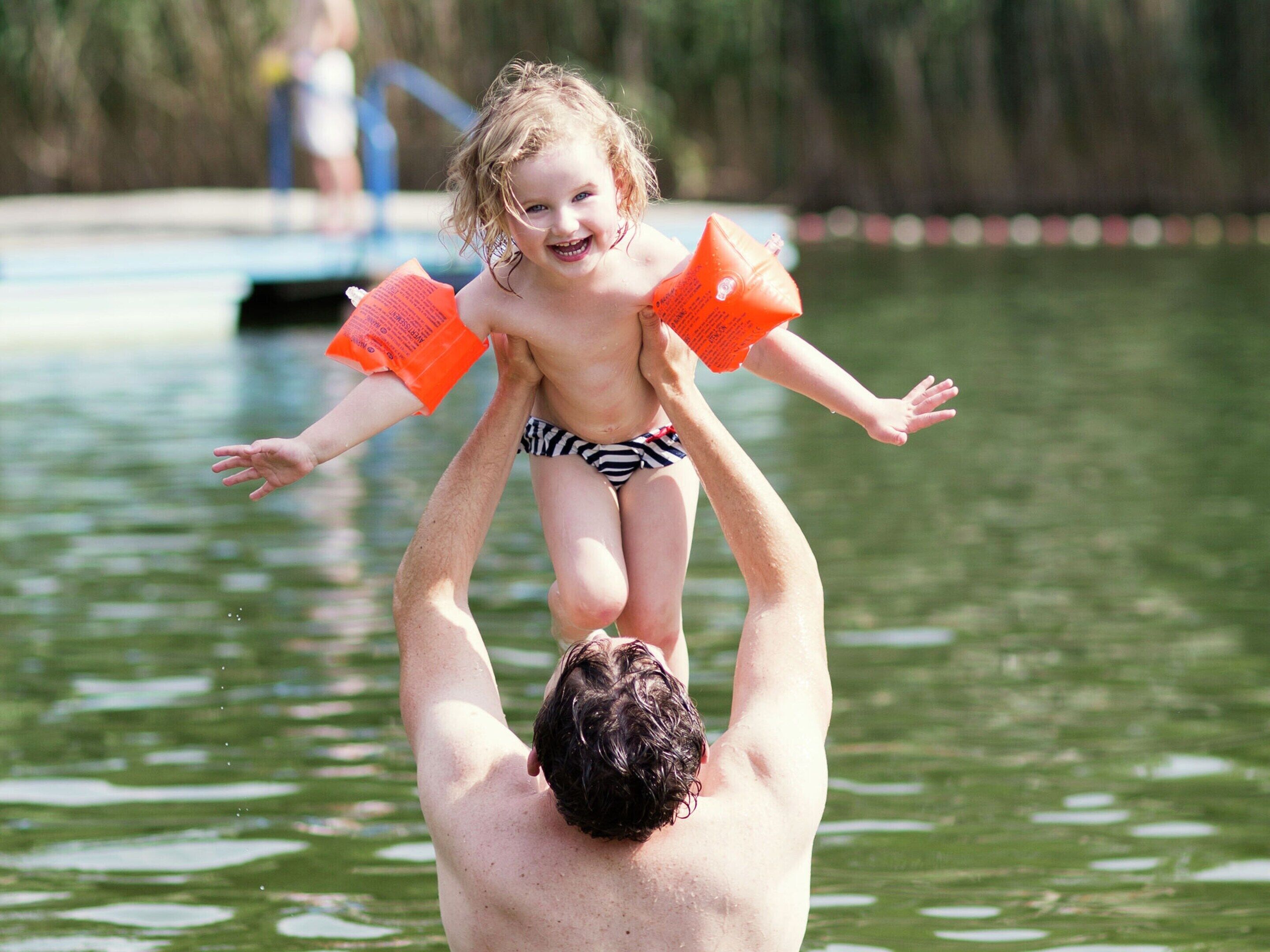 A man holding a child above water.