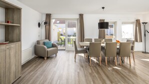 A modern living room with a dining area, wooden flooring, and a view to the outside. - Restyled Bungalow With 2 Bathrooms, Near the Beach (Noordwelle)