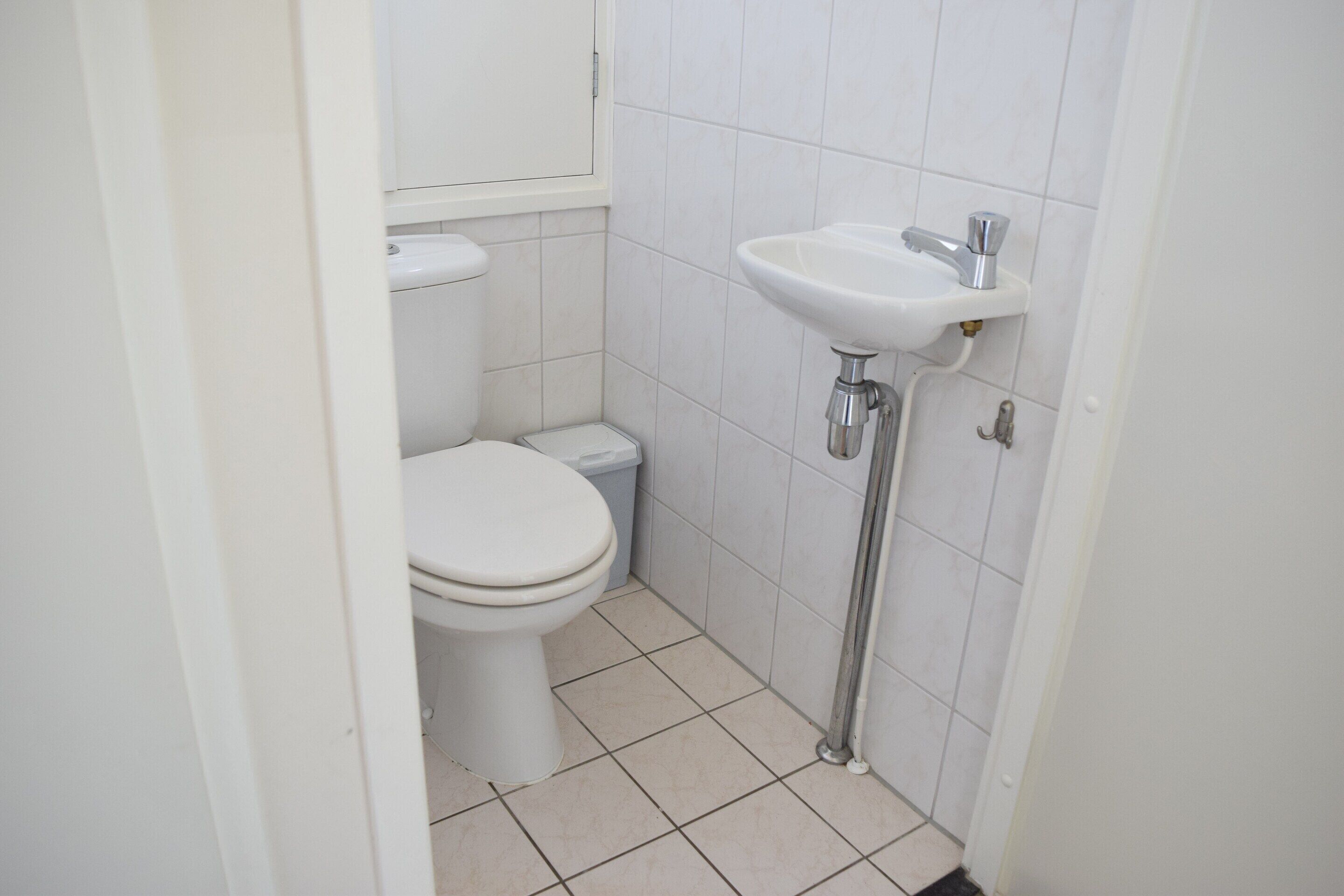 Een kleine, schone badkamer met toilet, wastafel en betegelde vloer.