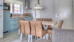 Una cucina moderna con mobili azzurri, un tavolo da pranzo in legno e sedie marroni.