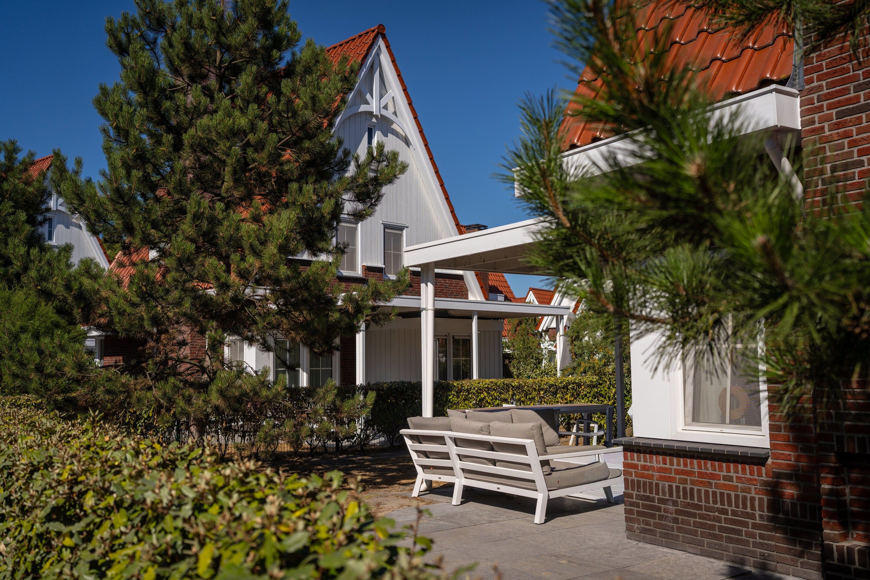A residential property with a brick exterior, white window frames, and a red-tiled roof.