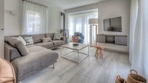 Un soggiorno moderno con un divano grigio, un tavolino da caffè, una TV e un camino.