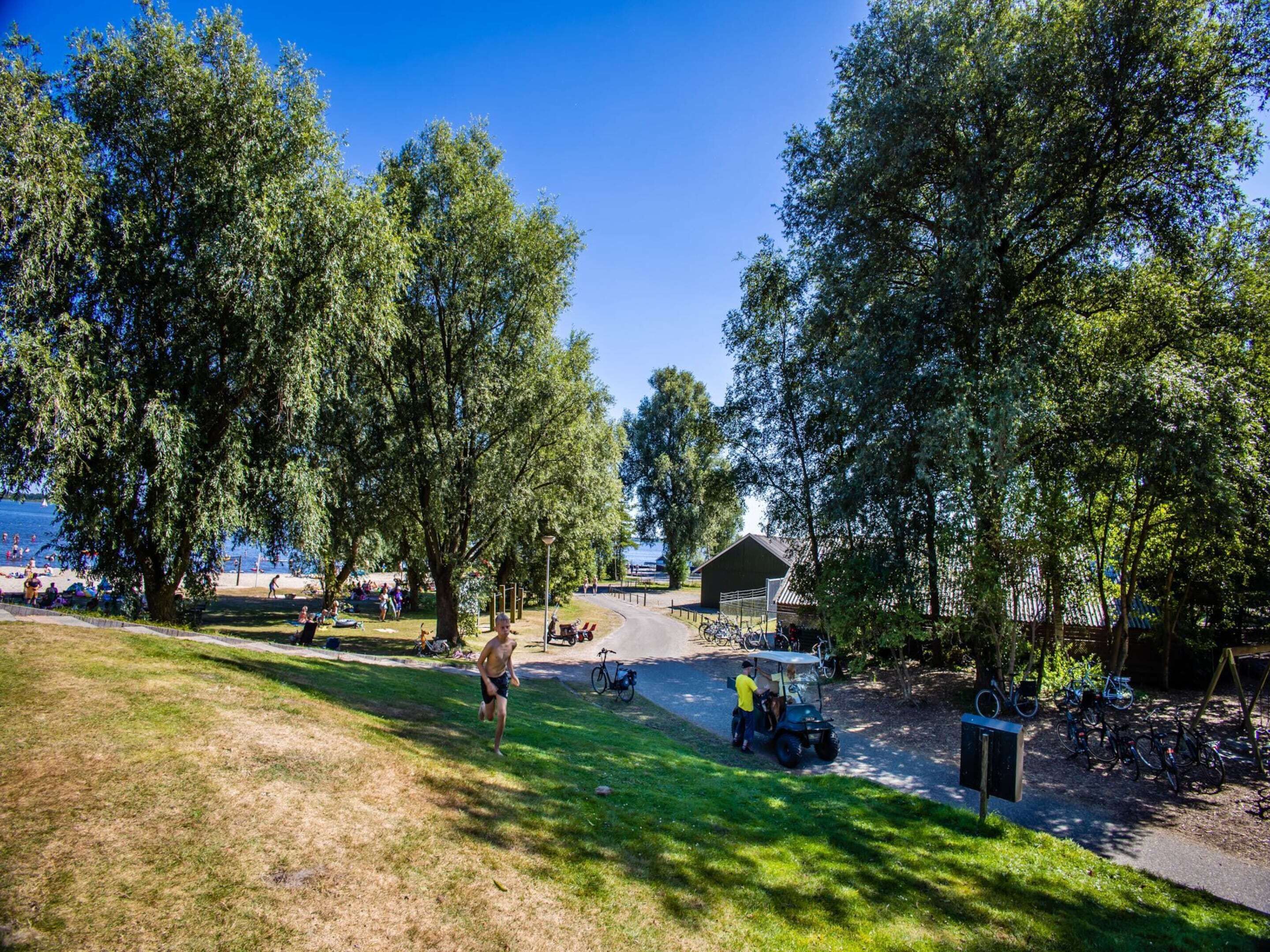 A park with a paved path, bicycles, and a small building.