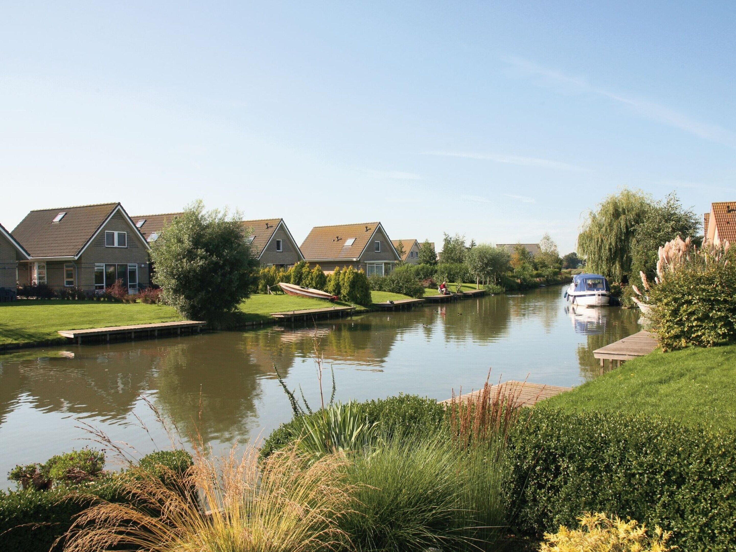 A canal with houses on one side and a boat docked on the other.