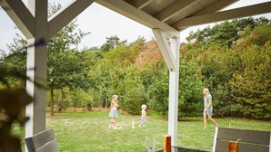 An outdoor patio with a table set for dining, surrounded by greenery and trees. - Great Villa With Sauna, Bubble Bath & Steam Shower (Roggel)