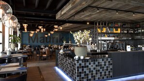 A modern bar area with a large sign reading "Maurik," a tiled counter, and a variety of seating arrangements. - Chalet With Terrace at the Lake and Beach (Maurik)