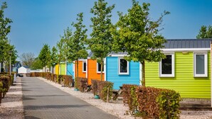 A row of colorful mobile homes with a paved road in between. - Chalet With Terrace at the Lake and Beach (Maurik)