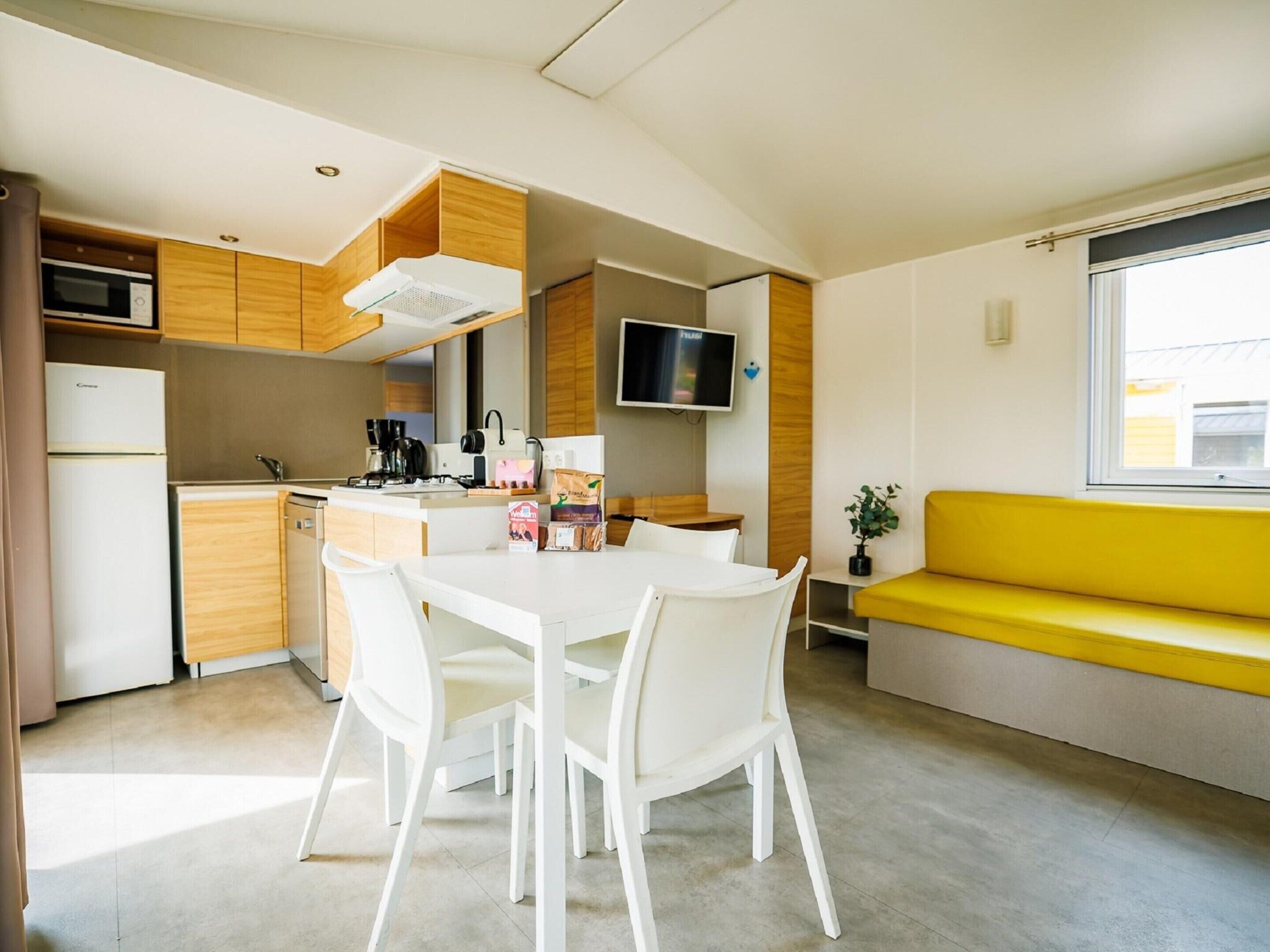 A compact kitchen with a dining area, a TV, and a window with a view.