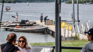 A lakeside view with a dock, boats, and people. - Chalet With Terrace at the Lake and Beach (Maurik)
