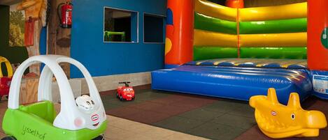 A children's play area with a bouncy castle, a toy car, and a toy dinosaur.