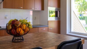 Una cocina con armarios de madera, un frutero en la encimera y una ventana con vistas a zonas verdes.