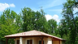 A single-story house with a tiled roof, a covered porch, and a small garden area. - Dordogne Escape w/ Shared Pools (Gavaudun)