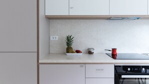 A kitchen with a countertop, a red pot, a digital clock, and a dish rack. - Jojo Apartment (Ljubljana)