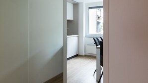 A modern, minimalist kitchen with white cabinets and a wooden floor. - Jojo Apartment (Ljubljana)
