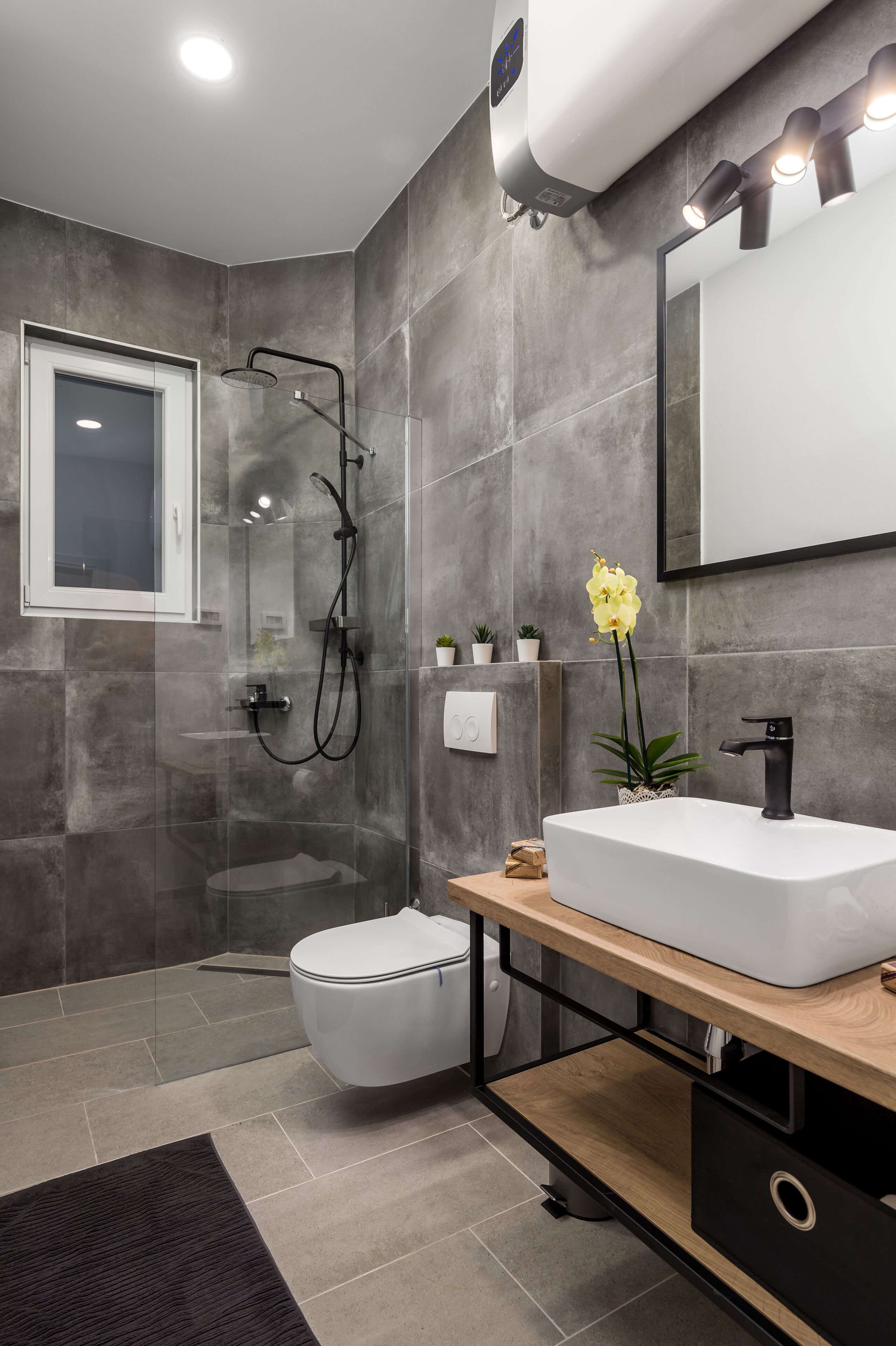 A modern bathroom with a glass-enclosed shower, a white sink, and a large mirror.