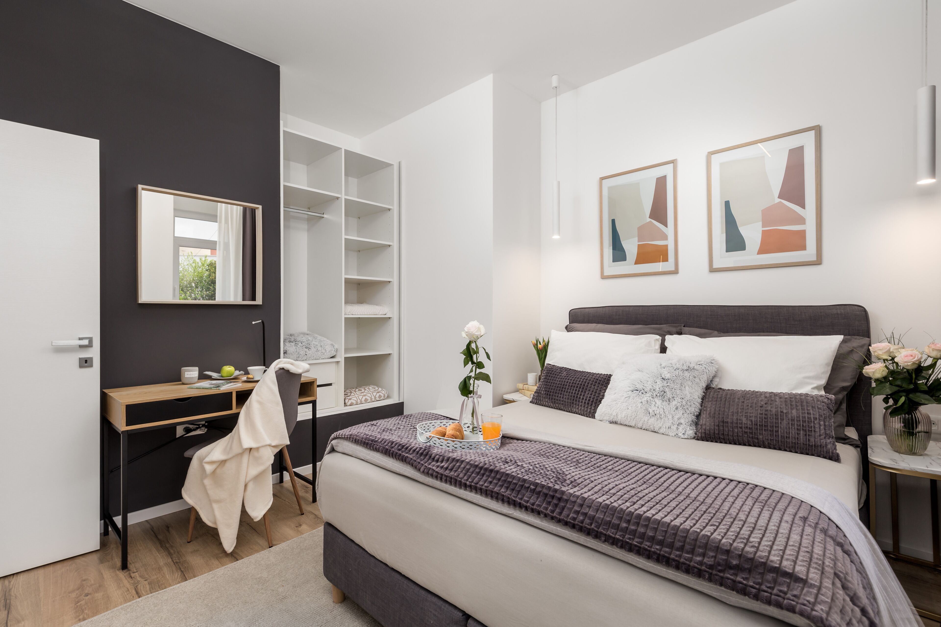 Un dormitorio moderno con cama, mesita de noche y escritorio con silla.