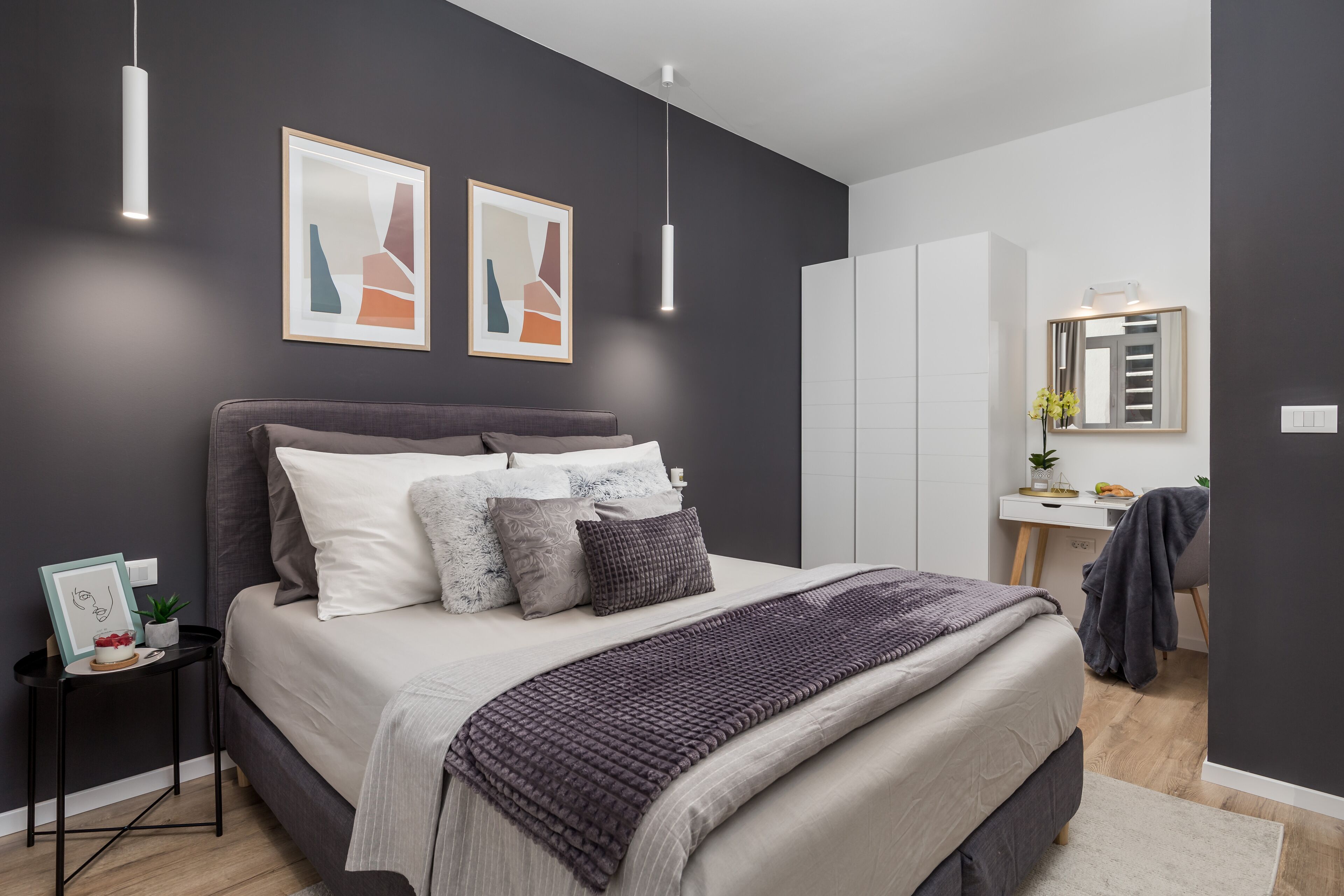 Ein modernes Schlafzimmer mit Bett, Nachttisch und Schreibtisch mit Spiegel.