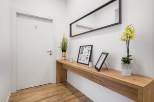 A hallway with a wooden console table, a white door, a mirror, and a potted plant.