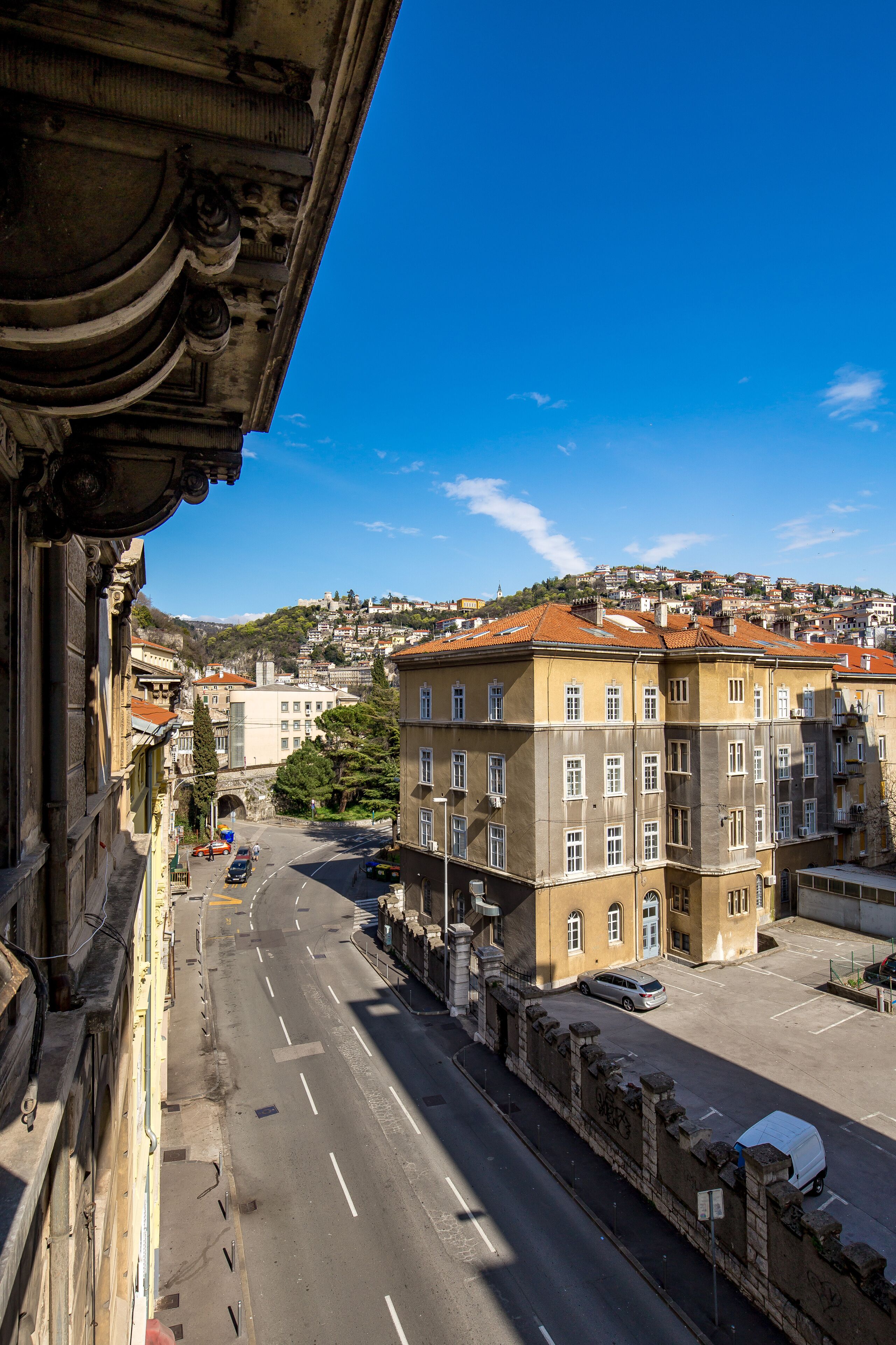 Vista callejera con edificios, cielo despejado y una colina distante.