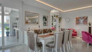 A modern dining area with a glass table, cushioned chairs, and a pendant light. - Wonderful private villa for 8 guests with A/C, private pool, WIFI, TV and terrace (Premantura)