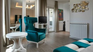 A modern living room with a teal armchair, a white round table, and a sofa with teal cushions. A flat-screen TV is mounted on the wall, and a radiator is visible. - Wonderful private villa for 8 guests with A/C, private pool, WIFI, TV and terrace (Premantura)