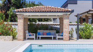 A pool area with a covered seating area, a tiled roof, and a brick wall. - Wonderful private villa for 8 guests with A/C, private pool, WIFI, TV and terrace (Premantura)