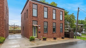 A two-story brick building with a green door, large windows, and a small front porch. - Razorblock North - 1 mi from DT - 3 blocks to UofA (Fayetteville)